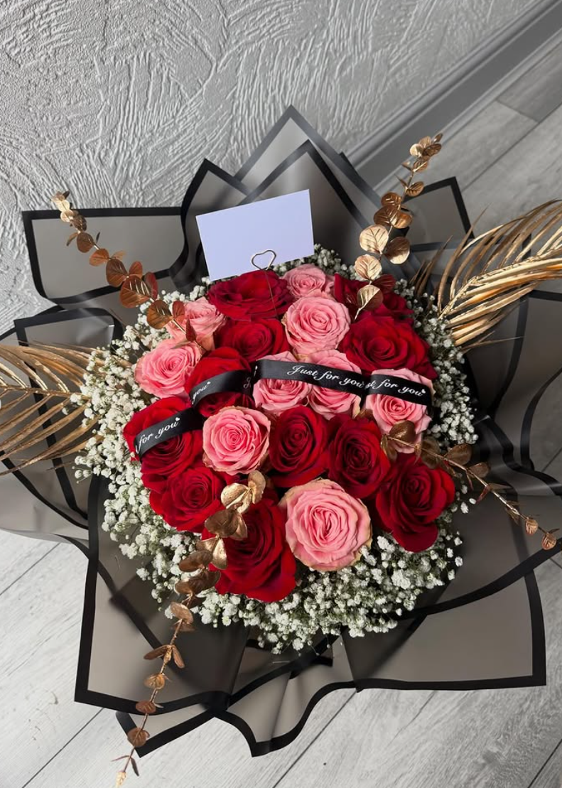 Red and pink rose bouquet in black wrap with gold foliage and gypsophila